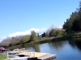 An outdoor view of a river with a dock and trees at Inverness Lodge in Inverness