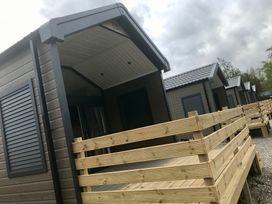 Multiple cabins with wooden decking and shutters at Inverness Lodge in Inverness