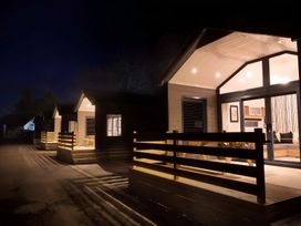 Three cabins with lit interiors and wooden railings at Inverness Lodge in Inverness