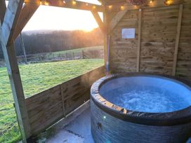 A hot tub in a wooden structure with a sunset view at Shepherds hut Dumfries