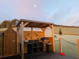 An outdoor area with a wooden structure and barbecue grill at Shepherds hut in Dumfries