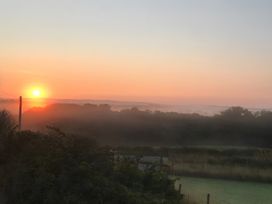 A sunrise over a misty field with trees at Shepherds hut Dumfries
