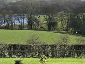 A view of a lake and fields with trees at Shepherds hut in Dumfries