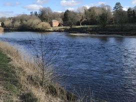 A river with a house and trees in the background at Shepherds hut Dumfries