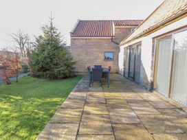 A garden with a table and chairs on a stone patio at Millstone cottage in Whitby