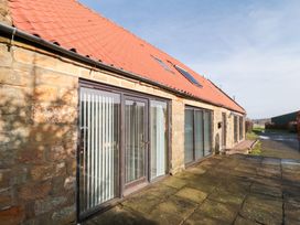 An outdoor area with sliding doors and stone walls at Millstone Cottage Sneaton Thorpe near Whitby
