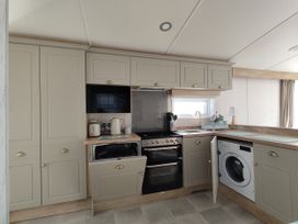 A kitchen with cabinets, stove, microwave, and washing machine at Harbour View in Poole