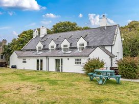 An outdoor view of a house with a picnic table and chairs at Bodior Garden Cottage Bach Holyhead