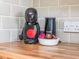 A coffee machine and milk frother with coffee pods at Bodior Garden Cottage Bach in Holyhead