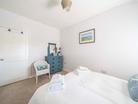 A bedroom with a bed and dresser at Bodior Garden Cottage Bach in Holyhead