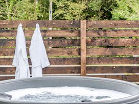 A hot tub with towels hanging on a wooden fence at Bodior Garden Cottage Bach Holyhead