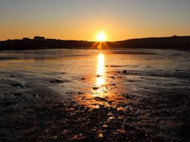 A sunset over water with rocks at Bodior Garden Cottage Bach in Holyhead