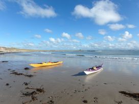 Two kayaks on a beach with ocean waves at Bodior Garden Cottage Bach Holyhead