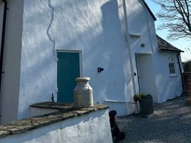 An exterior view showing a wall with a door and a milk jug at Bodior Garden Cottage Bach Rhoscolyn
