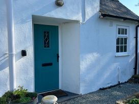 An entrance with a teal door and window at Bodior Garden Cottage Bach Rhoscolyn