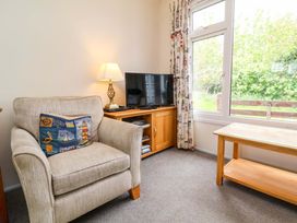 A living room with an armchair and television at Sea Breeze in Welcombe near Morwenstow