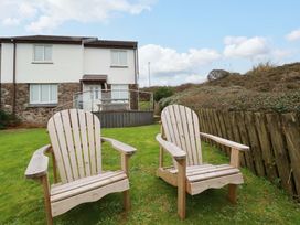 A garden with wooden chairs and a house at Poldreth Truro