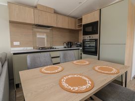 A kitchen with cabinets, appliances and a table at No.6 - The Pines Delamere