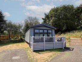 A mobile home with a deck and steps surrounded by grass and trees at The Pines 3 Bedrooms Delamere