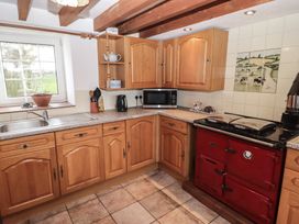 A kitchen with wooden cabinets and a red stove at Rhosgranog Cottage Llandeloy near Solva