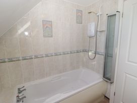 A bathroom with a tub and shower at Rhosgranog Cottage Llandeloy near Solva