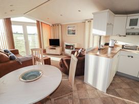 A living room with sofa and kitchen area at Rhosgranog Caravan in Llandeloy near Solva