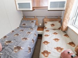 A bedroom with twin beds and a shelf at No 8 Hillcote Lodge in Cockermouth