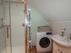 A bathroom with a shower washing machine and sink at Beachcombers Apt 11