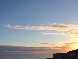 A sunset over the ocean with buildings at Beachcombers Apt 11 Watergate Bay near Newquay