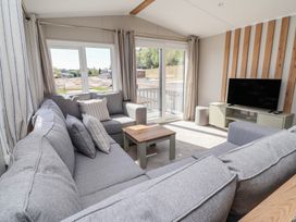 A living room with a sofa, TV, and large windows at No.20 - The Oaks in Delamere
