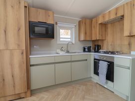 A kitchen with cabinets, microwave, stove and sink at No.20 - The Oaks in Delamere