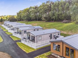 A row of holiday homes with trees in the background at The Oaks 2 Bedrooms Delamere