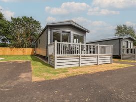 A mobile home with a deck and parking area at The Oaks 2 Bedrooms Delamere