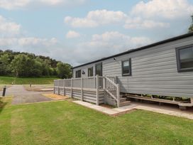 A mobile home with a deck and grass area at The Oaks 2 Bedrooms Delamere
