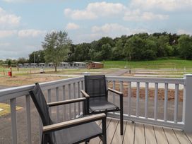 A deck with chairs overlooking a landscape at The Oaks 2 Bedrooms in Delamere