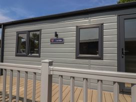 An exterior view of The Oaks cabin with windows and decking in Delamere