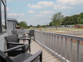 A deck area with chairs overlooking a campsite at The Oaks 3 Bedrooms in Delamere