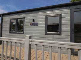 A cabin exterior with windows and a sign at The Oaks 3 Bedrooms in Delamere