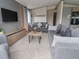 A living room with a sofa and television at Cedar Lodge 2 Bedrooms with hot tub in Delamere