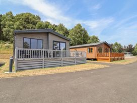 Two cabins with decking in a natural setting at Cedar Lodge 2 Bedrooms with hot tub Delamere