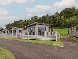 A cabin with decking and fence at Cedar Lodge 2 Bedrooms in Delamere