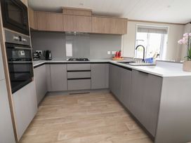 A kitchen with cabinets and appliances at Cedar Lodge 2 Bedrooms Delamere