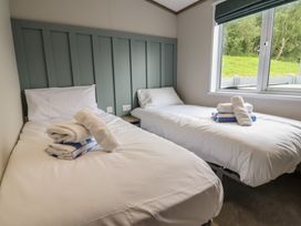 A bedroom with two beds and towels at Cedar Lodge 2 Bedrooms in Delamere