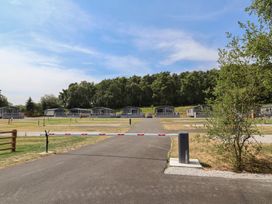 An outdoor view of lodges with trees in the background at Cedar Lodge 2 Bedrooms in Delamere