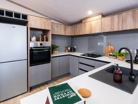 A kitchen with modern appliances and wood cabinetry at No 12 Whitefield Lodge Retreat in Northwich
