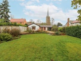 A garden with a house and church in the background at The Pantiles in Banham