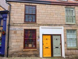 A building facade with a yellow door and a green door at Frida's Cottage in Whitby