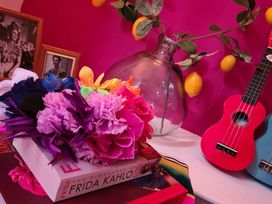 A tabletop with a book, artificial flowers, and musical instruments at Frida's Cottage in Whitby