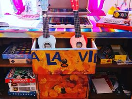 A living room with a desk featuring ukuleles and board games at Frida's Cottage in Whitby