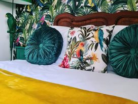 A bed with pillows and a parrot statue at Frida's Cottage in Whitby